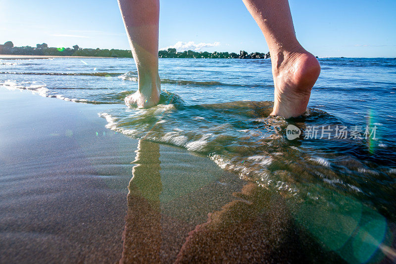 特写照片的人的脚的一个成年妇女走在水的边缘，Playa de Las America，加那利岛特内里费，西班牙-股票照片